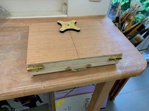 Underside of the Pochade box with a wooden bracket screwed into place.